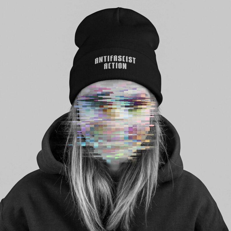 A woman wearing a Beanie with an embroidery in the lower front, saying 'Antifascist Action', her face is made unrecognisable with colourful glitches