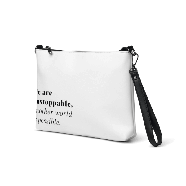 White faux-leather crossbody bag with dark grey hardware, with the sentence 'We are unstoppable, another world is possible.' printed on the lower left corner, turned 45 degrees clockwise