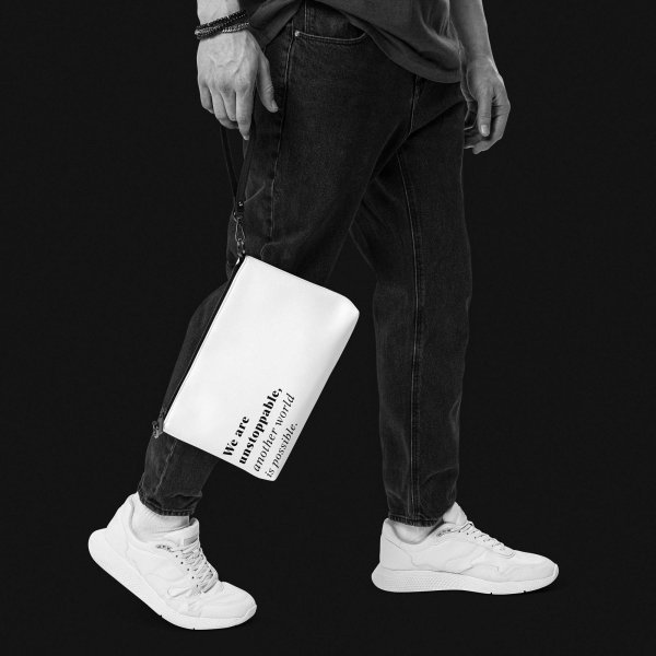 Man with dark jeans and bright sneakers, holding a white faux-leather shoulder bag against coal in his right hand, with the sentence 'We are unstoppable, another world is possible.' printed on the lower left corner in serif letters