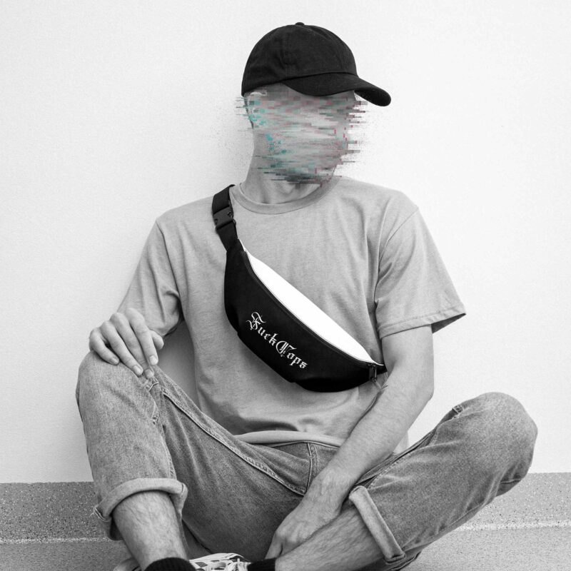 A man with a black cap, pullover and jeans, wearing a black and white belt bag with the words 'Fuck Cops' printed on it in white, his face is made unrecognizable with glitches