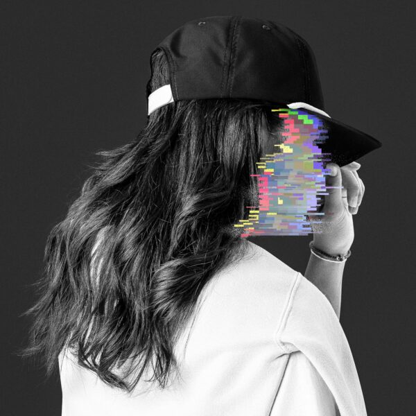 Side view of a woman, wearing a black cap and a white pullover, her face is made unrecognisable through colourful glitches